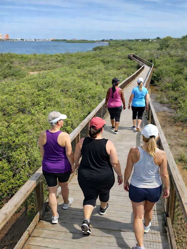 Women-only small group walking on a coastal boardwalk at Lorison wellness residency Florida.